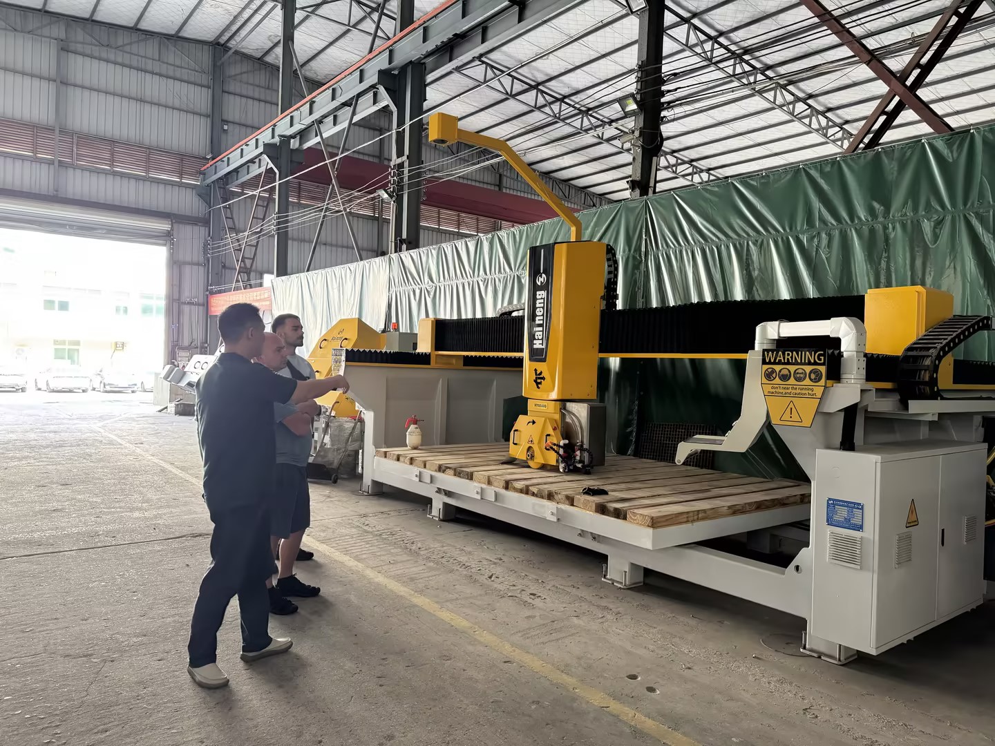 International clients inspecting the Haineng 5-axis CNC bridge saw during a factory visit.